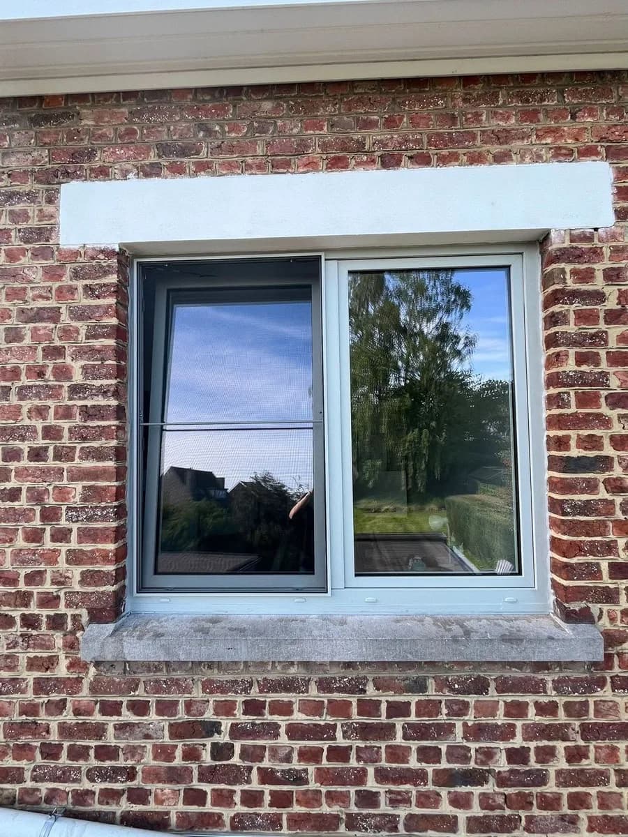 Châssis gris avec volet roulant intégré sur une façade en briques, réalisation CBL IMMO